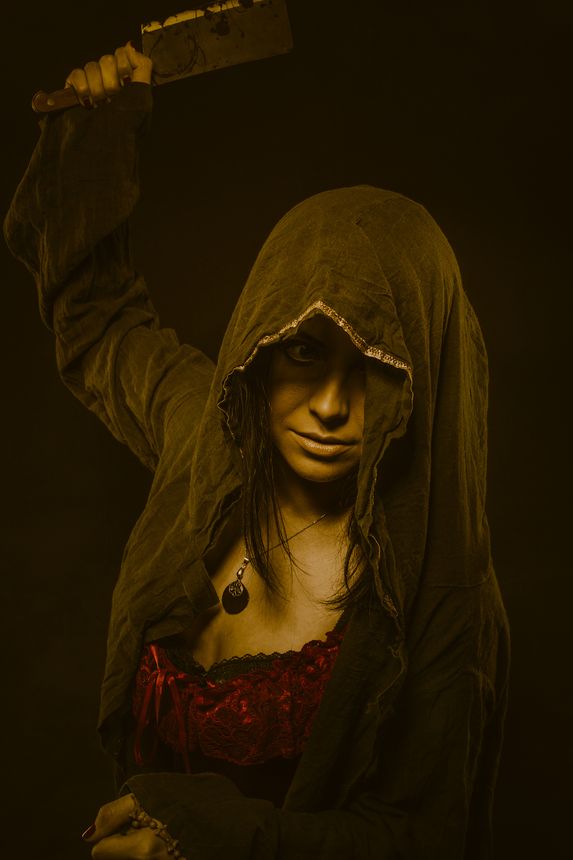 Pretty young woman posing in hood over dark background