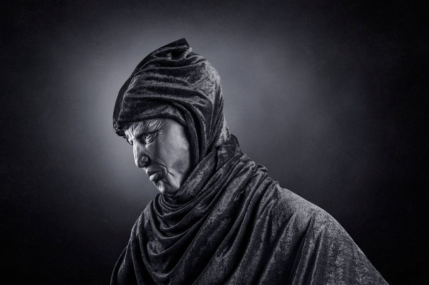 Scary figure with hooded cloak in the dark