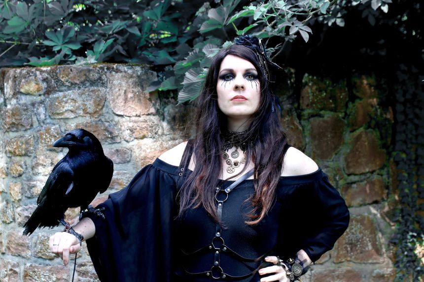 Fantasy photo of a woman dressed as a witch with a raven on her hand