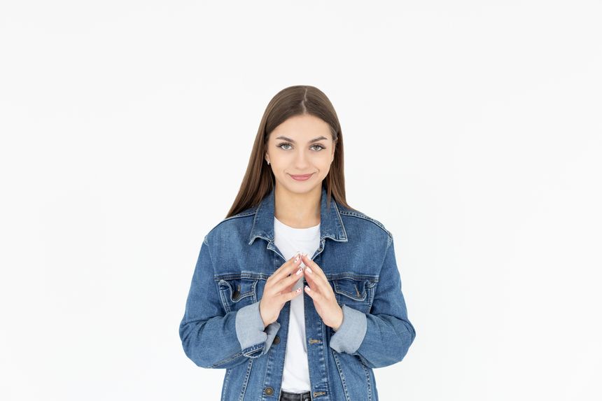 I have great evil plan. Confident and tricky woman in white t-shirt and jeans coat, holding fingers together and smirking at camera, having some bad intention in mind, planning to commit crime