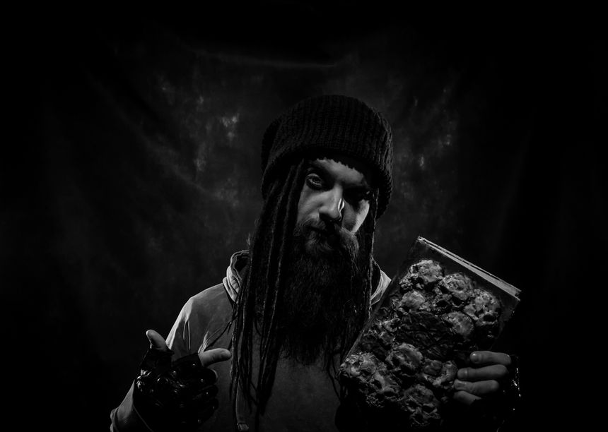 Bearded man with witch book posing over dark background