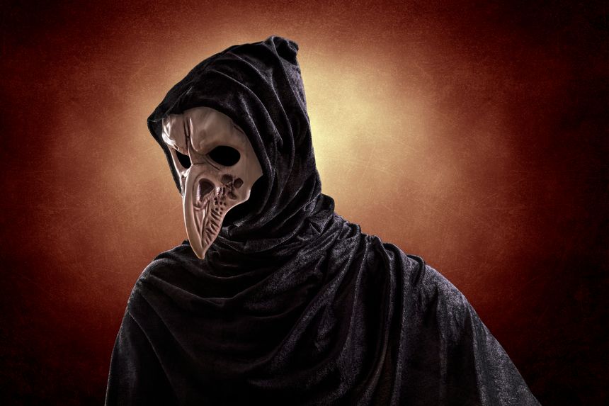 Creepy figure with animal bird skull over dark misty background